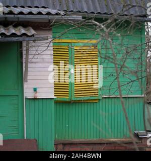 Apparentemente abbandonato casa dipinta in verde con persiane sulla finestra Foto Stock
