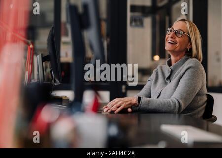 Felice coppia imprenditrice seduto alla scrivania in ufficio Foto Stock