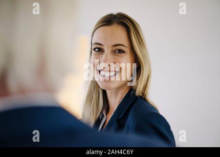 Ritratto di un sorridente giovane imprenditrice in ufficio con un collega Foto Stock