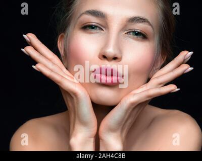 Close up ritratto di un bel blu eyed donna toucnig il suo volto. Isolato su bianco. Bellezza e cosmesi concetto. Foto Stock