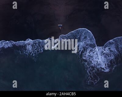 Vista aerea della giovane donna con la tavola da surf in spiaggia, Kedungu Beach, Bali, Indonesia Foto Stock