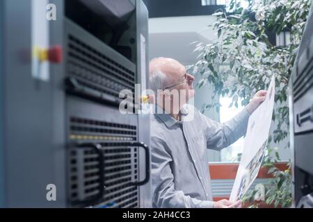 Manager che lavora in casa di stampa, controllo carta Foto Stock