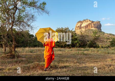 Monaco con il suo ombrello con la Roccia di Sigiriya in background in Sri Lanka Foto Stock