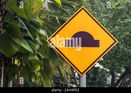 Strada artificiale rugosità; auto segnale di limite di velocità tra vegetazione tropicale Foto Stock