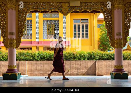 Monaco a piedi tra le colonne del tempio dedicato al Buddha sdraiato, nell Arcidiocesi di Yangon, Myanmar Foto Stock