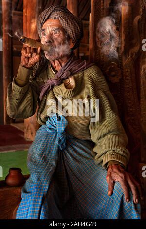 Uomo anziano fumatori di sigaro locale noto come cheroot, in Bagan, Myanmar Foto Stock