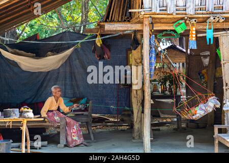 Donna anziana oscilla la culla baby, in Bagan, Myanmar Foto Stock