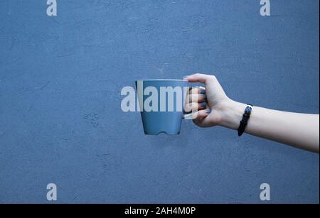 Mockup di femmine della mano che tiene una tazza di caffè isolato su sfondo blu Foto Stock