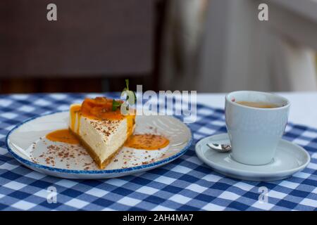 Mandarin topping cheesecake e la tazza di caffè sul tavolo in condizioni di luce diurna Foto Stock
