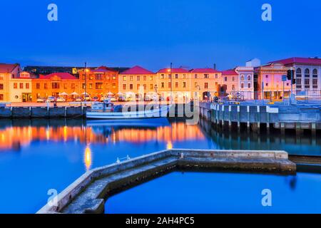 Molo di cemento e pontili sul porto di Hobart Sullivan's Cove al tramonto con case storiche che riflette ancora in acque e unica barca da pesca. Foto Stock