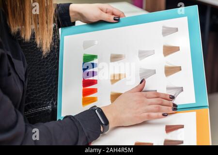 Le mani di uno stilista o client azienda tavolozza di colorante per capelli di campioni in un salone di bellezza, vicino. Foto Stock