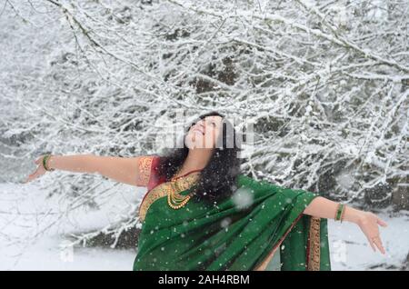 Tradizionalmente condita fiducioso donna indiana godendo di nevicata Foto Stock