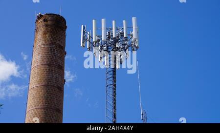 Ciminiere in mattoni e la radio o la torre cellulare contro un cielo blu. Fergus Falls, Minnesota. Foto Stock