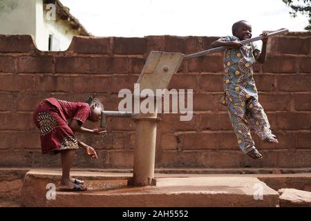 Bambini Africani Giocando Al Pompa Dell'Acqua Del Villaggio Foto Stock