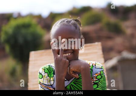 Bella ragazza africana con un grande sorriso rendendo il segno di pace Foto Stock