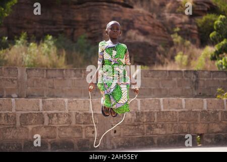 Poco ragazza africana con un bellissimo abito verde concentrandosi sulla sua prestazione di salto Foto Stock