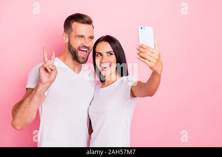 Ritratto di sua egli ha due belle attraente bella affascinante Allegro vivace coniugi, utilizzando tenendo rendendo selfie mostra v-segno isolato uovere Foto Stock