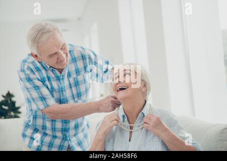 Ritratto di sua egli ha due belle attraente bella allegra allegra, positivo felici le persone nonno mettendo nuova collana su granny in luce bianco int Foto Stock