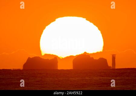 Gli aghi, Isle of Wight, Regno Unito. Il 25 dicembre 2019. Regno Unito Meteo. Il sole sorge da dietro gli aghi faro sull isola di Wight all alba del giorno di Natale. Credito Foto: Graham Hunt/Alamy Live News Foto Stock