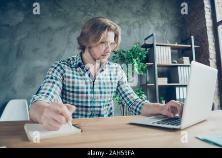 Profilo foto a lato dell'esperto con capelli biondi texting avente note book indossa, a scacchi plaid shirt eyewear occhiali sit in interni Foto Stock