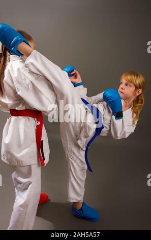 Sport Karate lotta a due bambine in kimono bianco in rosso una seconda in blu kit di protezione Foto Stock