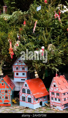 Una vista ravvicinata di splendidamente decorate albero di Natale con a struttura mista in legno e muratura case modello al di sotto Foto Stock