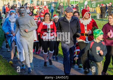 Chippenham, Wiltshire, Regno Unito. 25th dicembre 2019. I corridori in vestito di fantasia sono ritratti mentre prendono parte ad un parkrun 5km di Natale di mattina presto in Monkton Park, Chippenham, Wiltshire. 400-500 persone hanno partecipato all'evento con molti vestirsi in abito elegante. Credito: Lynchpics/Alamy Live News Foto Stock