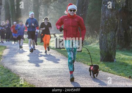 Chippenham, Wiltshire, Regno Unito. 25th dicembre 2019. I corridori sono raffigurati mentre prendono parte ad un parkrun 5km di Natale di mattina presto in Monkton Park, Chippenham, Wiltshire. 400-500 persone hanno partecipato all'evento con molti vestirsi in abito elegante. Credito: Lynchpics/Alamy Live News Foto Stock