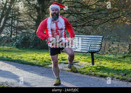 Chippenham, Wiltshire, Regno Unito. 25th dicembre 2019. Un corridore in vestito di fantasia è ritratto mentre prende parte ad un parkrun 5km di Natale di mattina presto in Monkton Park, Chippenham, Wiltshire. 400-500 persone hanno partecipato all'evento con molti vestirsi in abito elegante. Credito: Lynchpics/Alamy Live News Foto Stock