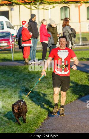 Chippenham, Wiltshire, Regno Unito. 25th dicembre 2019. Un corridore in vestito di fantasia è ritratto mentre prende parte ad un parkrun 5km di Natale di mattina presto in Monkton Park, Chippenham, Wiltshire. 400-500 persone hanno partecipato all'evento con molti vestirsi in abito elegante. Credito: Lynchpics/Alamy Live News Foto Stock