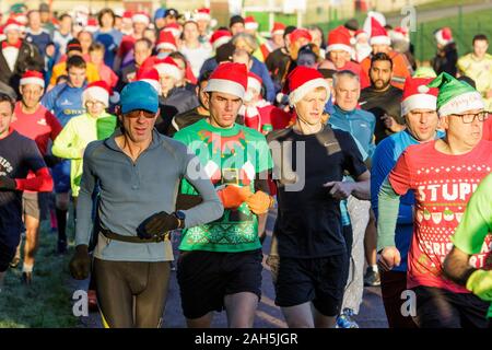 Chippenham, Wiltshire, Regno Unito. 25th dicembre 2019. I corridori sono raffigurati mentre prendono parte ad un parkrun 5km di Natale di mattina presto in Monkton Park, Chippenham, Wiltshire. 400-500 persone hanno partecipato all'evento con molti vestirsi in abito elegante. Credito: Lynchpics/Alamy Live News Foto Stock