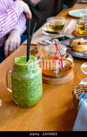 Bicchiere di verde frullati con Freschi Tè verde su un tavolo in un bar. Foto Stock