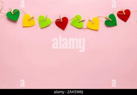 Cuori colorati sparsi con clothespin sul rosa pastello sfondo. Valentines, Giornata della madre, compleanno biglietti di auguri, invito celebrazione concep Foto Stock