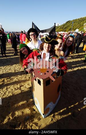 Circa 1.200 persone hanno preso parte all'annuale del giorno di Natale Macmillan Caring Bianco Natale Dip 25/12/2019. La gente in costume e su una luminosa mattina di sole corse in mare su Boscombe fronte mare. La raccolta di fondi per la cura Macmillian localmente le cure palliative unità in Christchurch, questo evento è cresciuto nel corso degli anni. Circa un quarto di milione di è stata sollevata poiché gli eventi inizi. Foto Stock