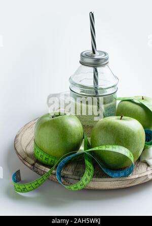 Mele Verdi e il succo di mela con nastro di misurazione per il controllo del peso nella dieta Foto Stock