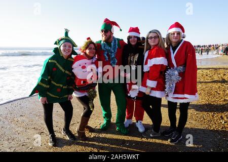 Circa 1.200 persone hanno preso parte all'annuale del giorno di Natale Macmillan Caring Bianco Natale Dip 25/12/2019. La gente in costume e su una luminosa mattina di sole corse in mare su Boscombe fronte mare. La raccolta di fondi per la cura Macmillian localmente le cure palliative unità in Christchurch, questo evento è cresciuto nel corso degli anni. Circa un quarto di milione di è stata sollevata poiché gli eventi inizi. Foto Stock