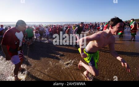 Circa 1.200 persone hanno preso parte all'annuale del giorno di Natale Macmillan Caring Bianco Natale Dip 25/12/2019. La gente in costume e su una luminosa mattina di sole corse in mare su Boscombe fronte mare. La raccolta di fondi per la cura Macmillian localmente le cure palliative unità in Christchurch, questo evento è cresciuto nel corso degli anni. Circa un quarto di milione di è stata sollevata poiché gli eventi inizi. Foto Stock