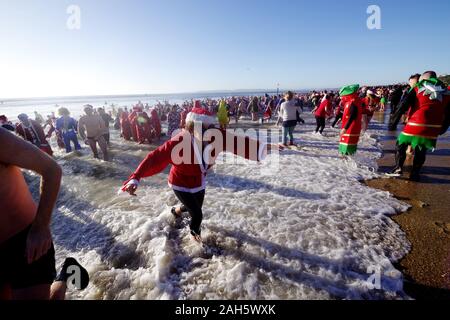 Circa 1.200 persone hanno preso parte all'annuale del giorno di Natale Macmillan Caring Bianco Natale Dip 25/12/2019. La gente in costume e su una luminosa mattina di sole corse in mare su Boscombe fronte mare. La raccolta di fondi per la cura Macmillian localmente le cure palliative unità in Christchurch, questo evento è cresciuto nel corso degli anni. Circa un quarto di milione di è stata sollevata poiché gli eventi inizi. Foto Stock