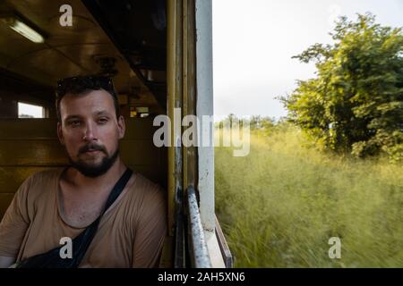 Un uomo seduto sul treno che viaggia da un luogo ad un altro Foto Stock