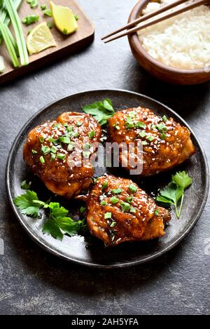 Grigliata di cosce di pollo sulla piastra su pietra scura sullo sfondo. Gustosi piatti in stile asiatico. Foto Stock