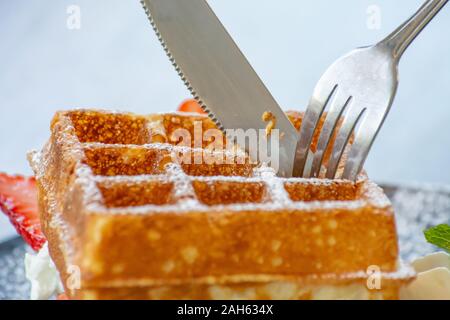 Waffle Strawerry panna fresca nella piastra nera su un tavolo di legno. Foto Stock