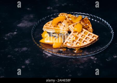 Cialde con pesche per la colazione su uno sfondo nero. Foto Stock