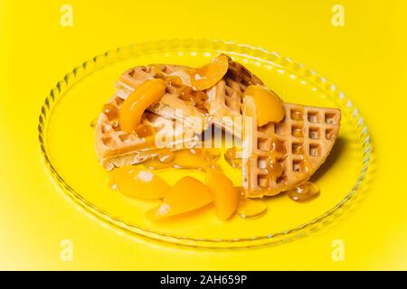 Cialde con pesche per la colazione su uno sfondo giallo. Foto Stock
