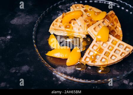 Cialde con pesche per la colazione su uno sfondo nero. Foto Stock