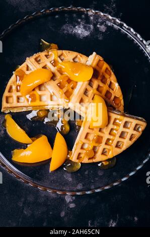 Cialde con pesche per la colazione su uno sfondo nero. Foto Stock