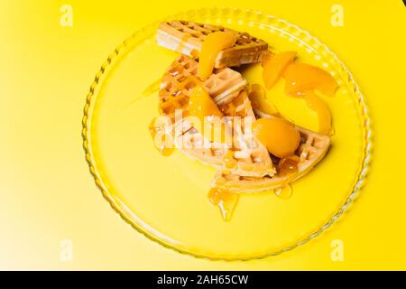 Cialde con pesche per la colazione su uno sfondo giallo. Foto Stock