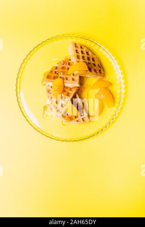 Cialde con pesche per la colazione su uno sfondo giallo. Foto Stock