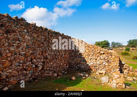 Il vecchio muro di pietra in un campo verde, bue sky con nuvole bianche. Soleggiata giornata autunnale a Siviglia, Spagna Foto Stock