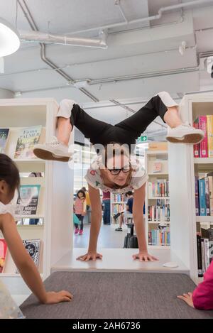 10 NOV 2019: Un contortionist intrattiene i bambini presso l'apertura del nuovo edificio della Borsa e la città di Sydney Libreria nel Darling Square, Sydney Foto Stock