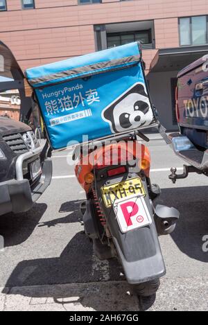 Un affamato Panda consegna moto con una piastra P (provvisorio patente) attaccato sul retro, è strettamente parcheggiata tra due vetture a Sydney Foto Stock